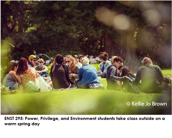   Power, Privilege, and Environment students take a class outside on a warm spring day